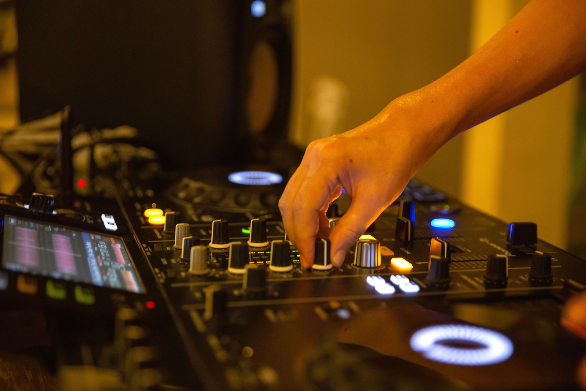 Unrecognizable hand of female dj mixing music tracks at party